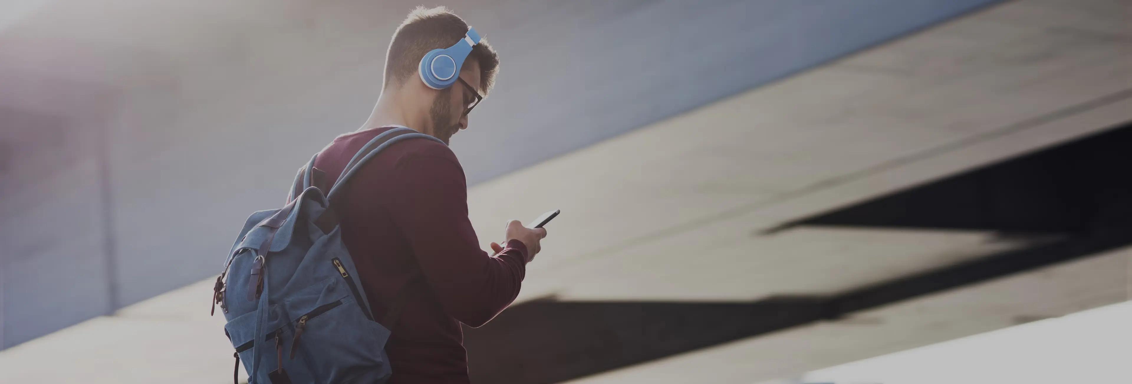 Imagem de um homem com fones de ouvido mexendo no celular