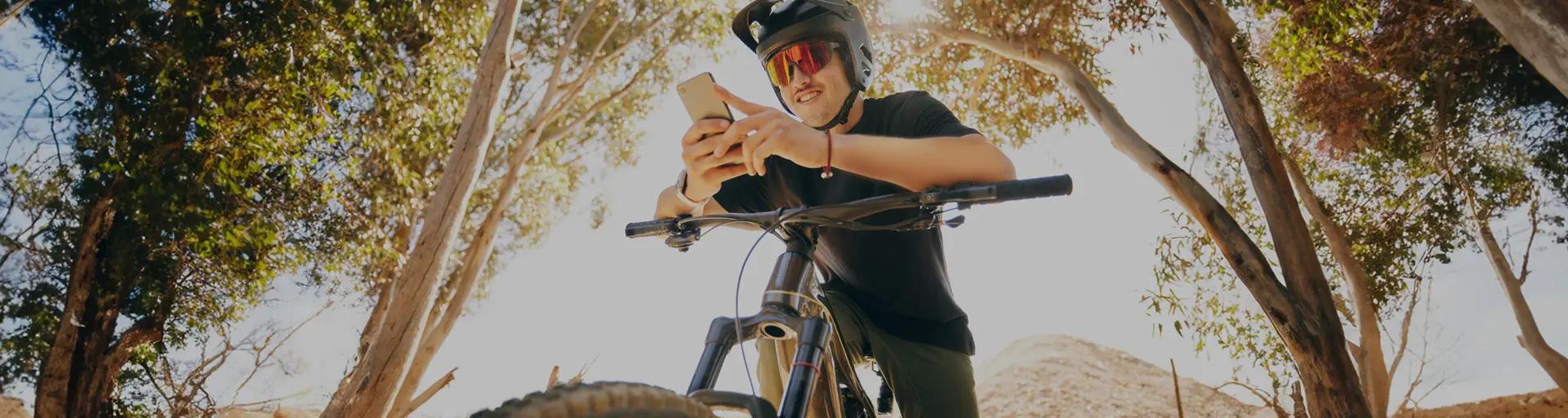 Imagem de um homem em cima de uma bicicleta segurando um celular